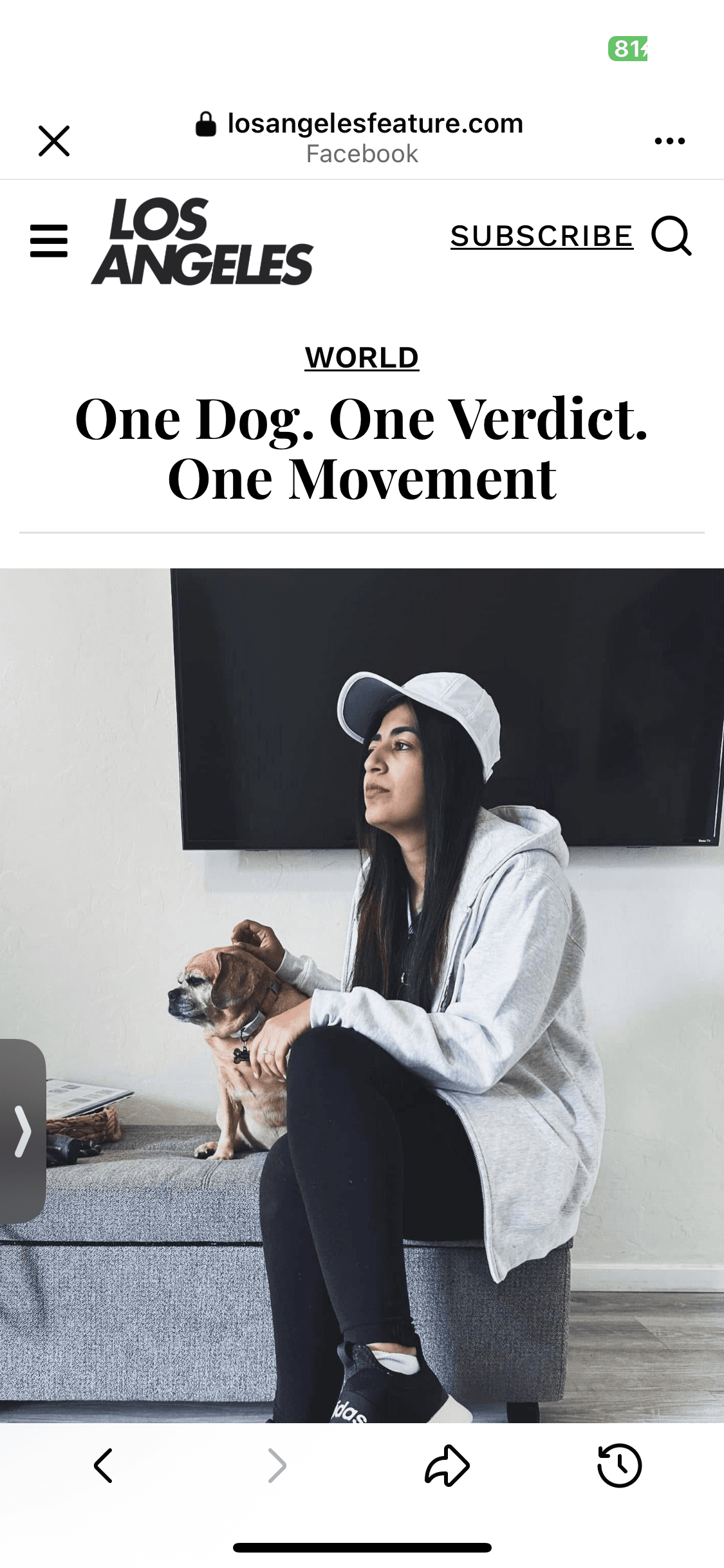 Woman in a white cap and grey hoodie sits beside her small tan dog.