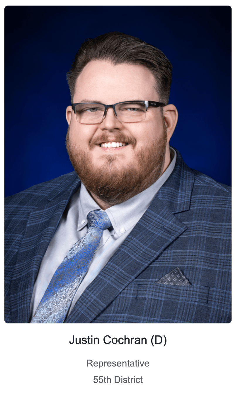 Justin Cochran, a smiling man with glasses and beard, wearing a blue plaid suit.